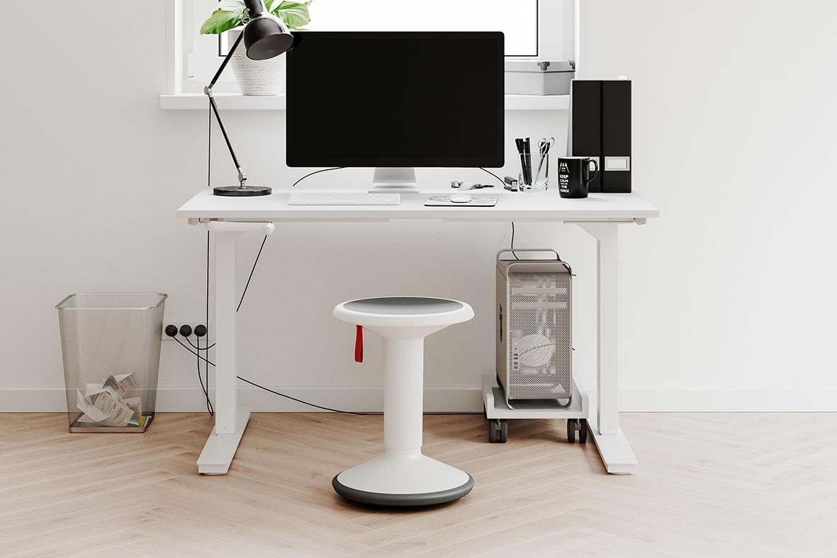 Sadelstol i vitt med svart balanspall framför skrivbord med dator och tillbehör i ett hemmakontor