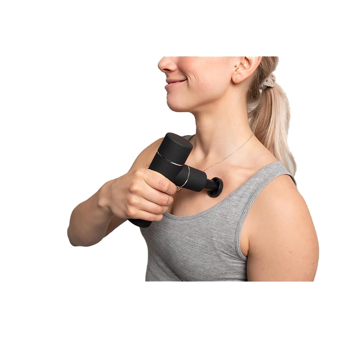 Kvinna använder massagepistol på axeln för att lindra muskelspänningar