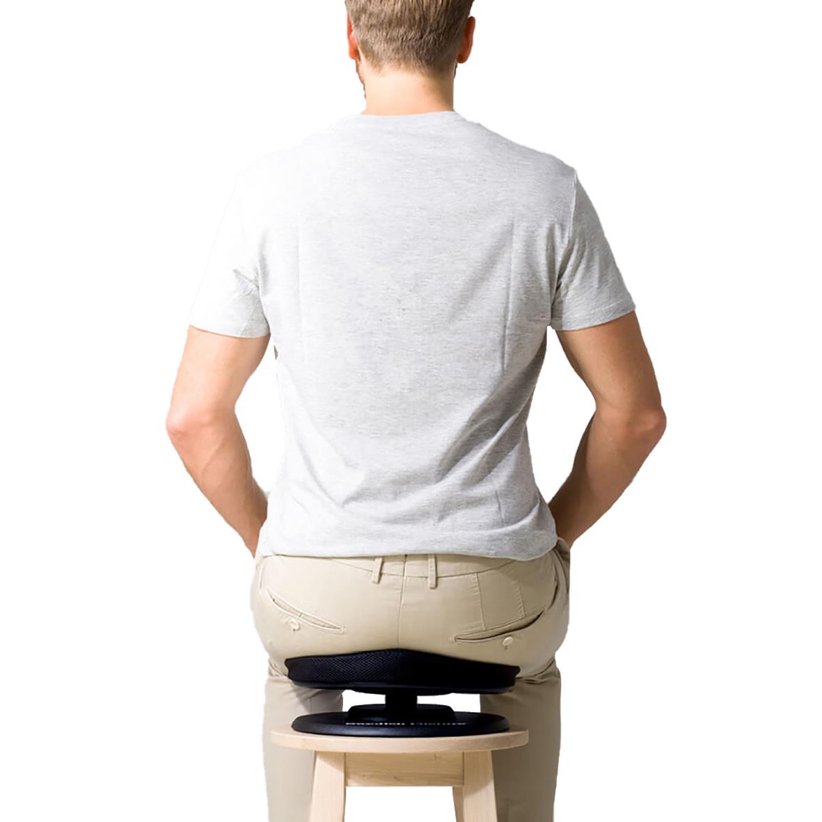 Person som sitter på en stol med en balanskudde under sittbenen för att förbättra hållningen