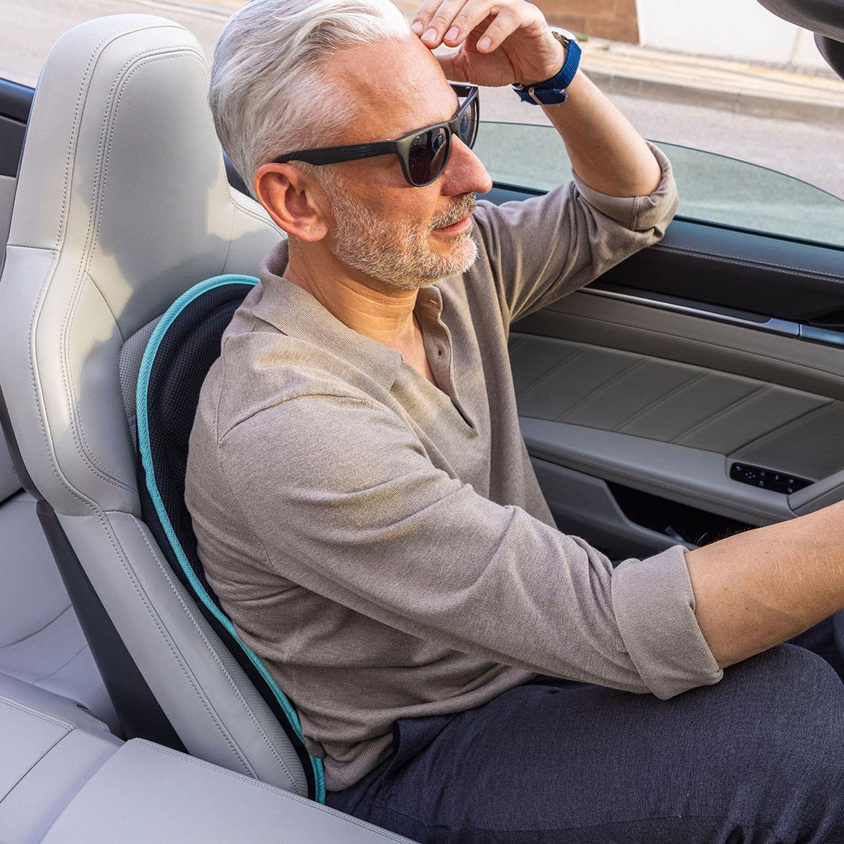 Man som kör bil med Medivon Cosy Mesh Go massagekudde i bilstolen