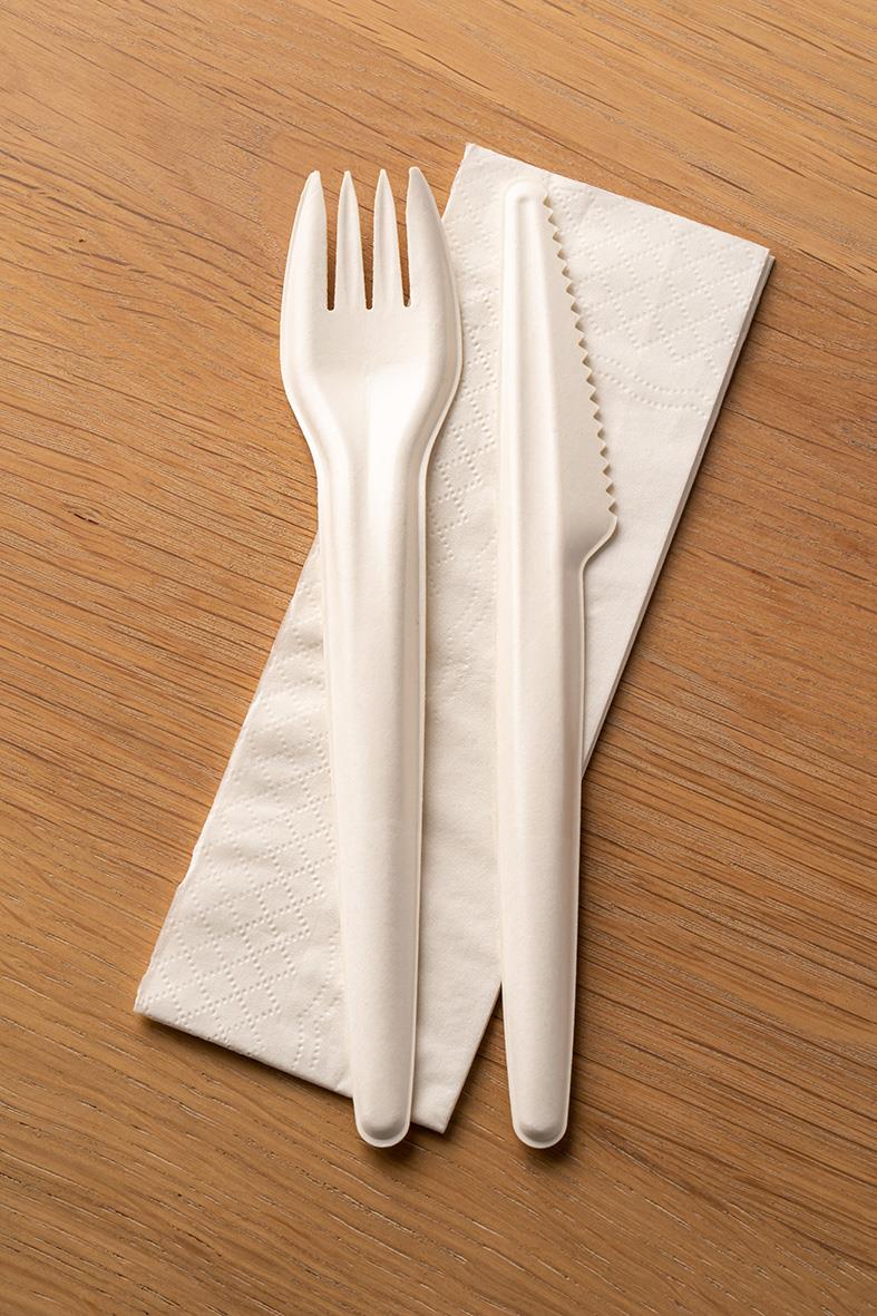 Bestickpåse med kniv, gaffel och servett på träbord