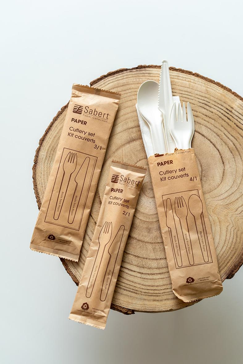 Bestickpåse med kniv, gaffel och servett på träskiva