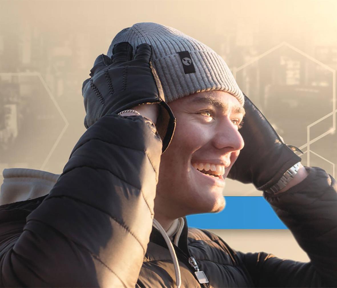 Ung man i mössa och jacka, ler och ser glad ut, utomhus i vintermiljö