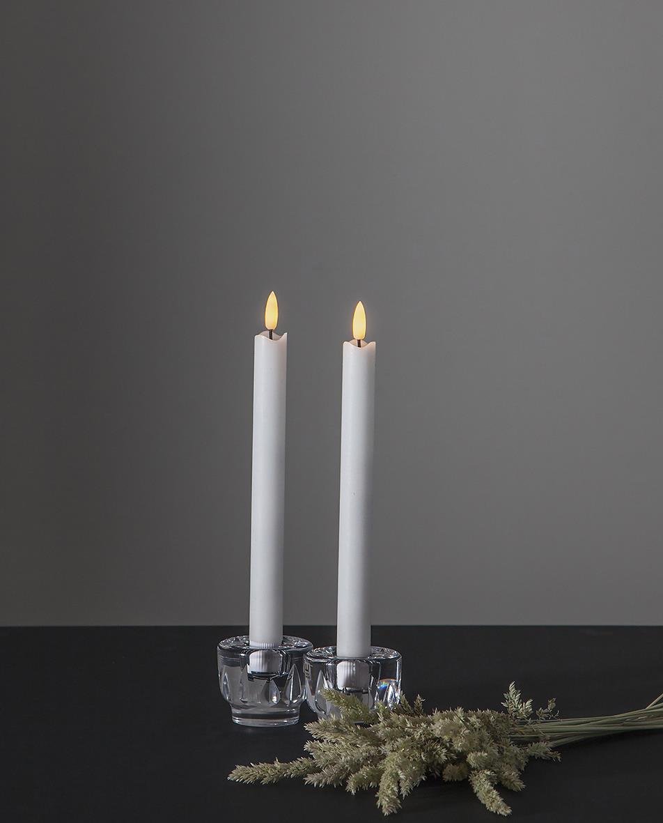 Två vita LED-eldljus på 25 cm i små glas, dekorerade med torkade växter framför en grå vägg