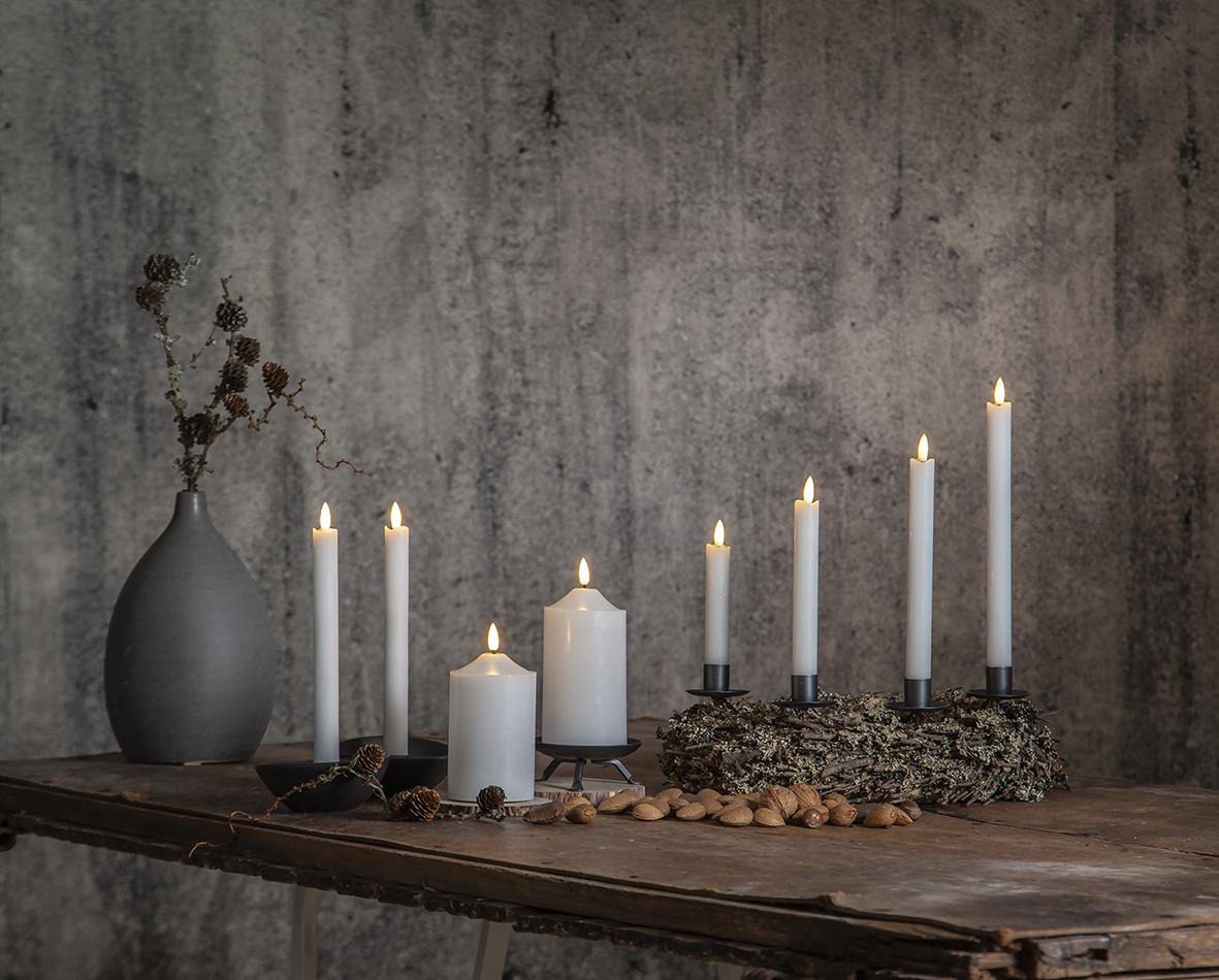 Vit LED blockljus i olika höjder på träbord mot en grå vägg