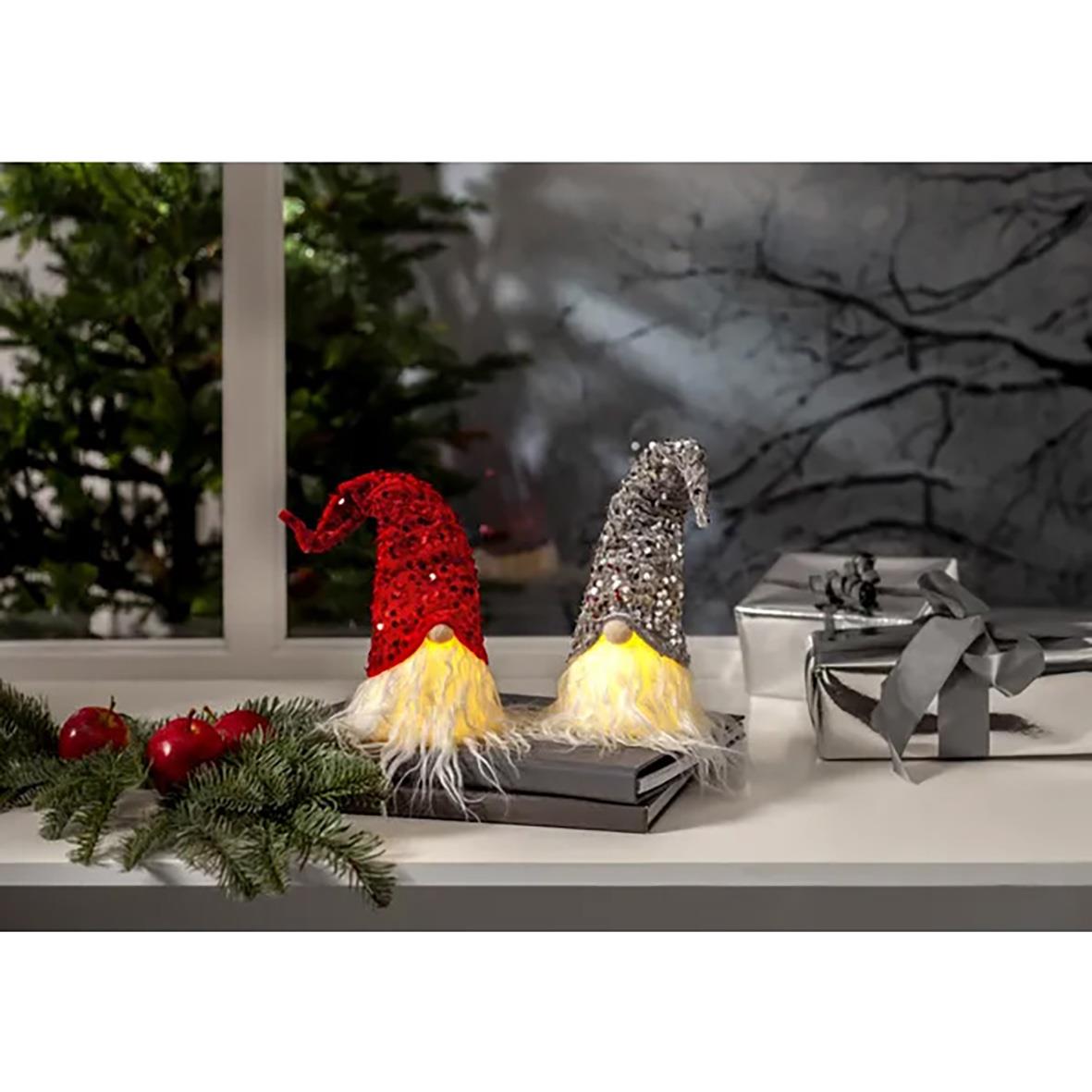 Två tomtefigurer i silver och rött med fluffiga fötter, dekoration på fönsterbräda med julgransgrenar och presenter