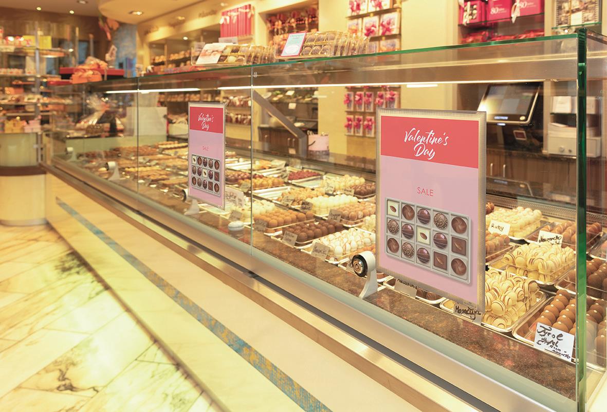 Vitrinskåp med bakverk och godsaker, skyltar för specialerbjudanden i en butik