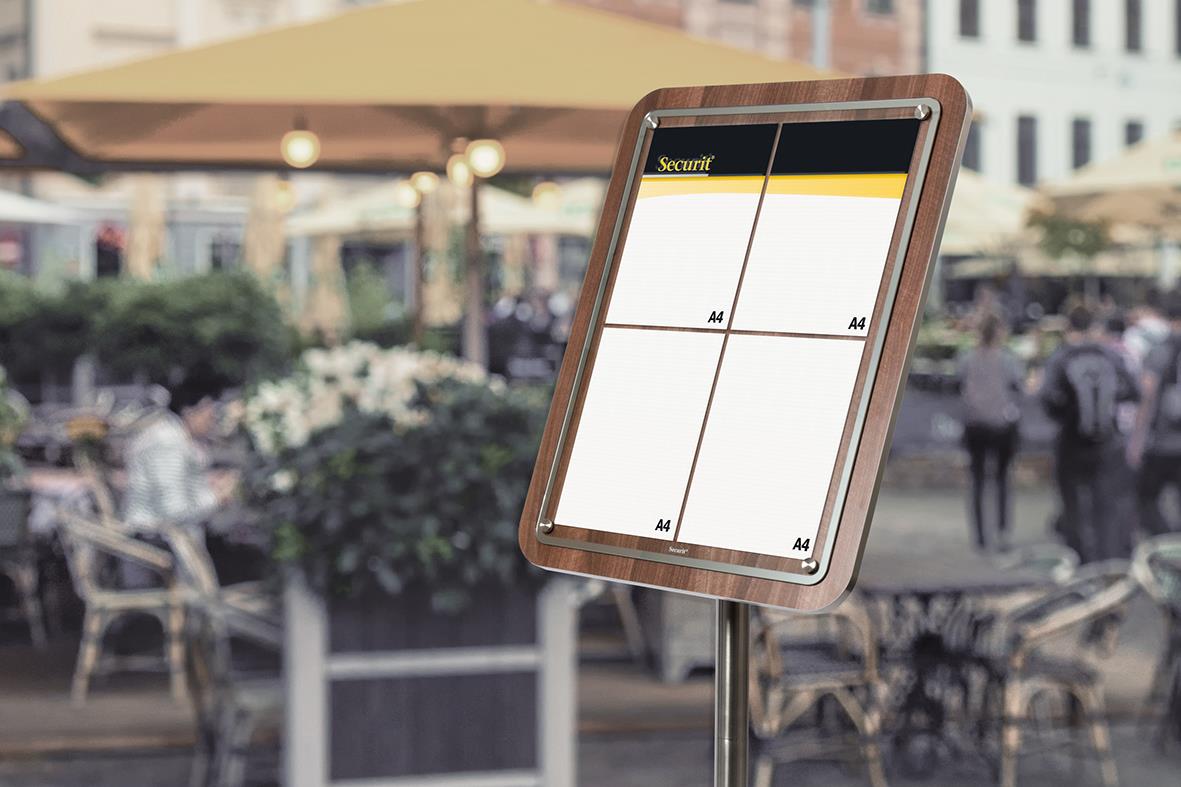 Display till informationsställ med LED, visar fyra A4-sidor, valnötssarg, utomhusmiljö med människor och uteservering