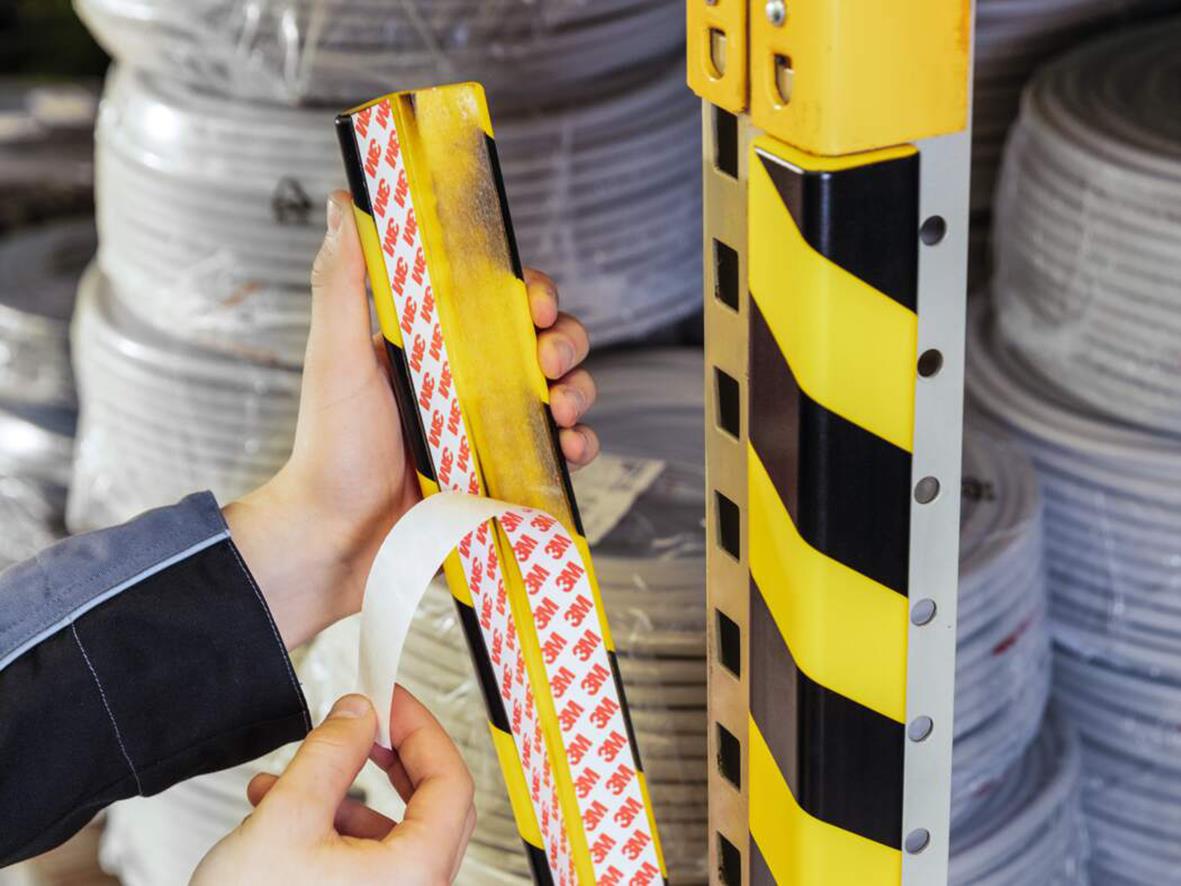 Hörnskydd i gul och svart färg monterat på en stolpe, används för säkerhet och skydd i arbetsmiljö