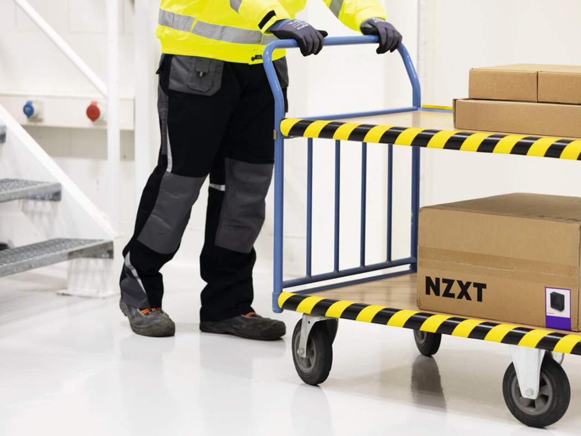 Person flyttar kartonger på en vagn med rörskydd Durable P30 Gul/Svart 1000x50mm i en lagermiljö