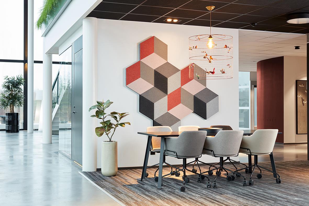 Väggdekoration med kubiska ljudabsorberande paneler i rött, beige och svart i ett modernt kontorsutrymme