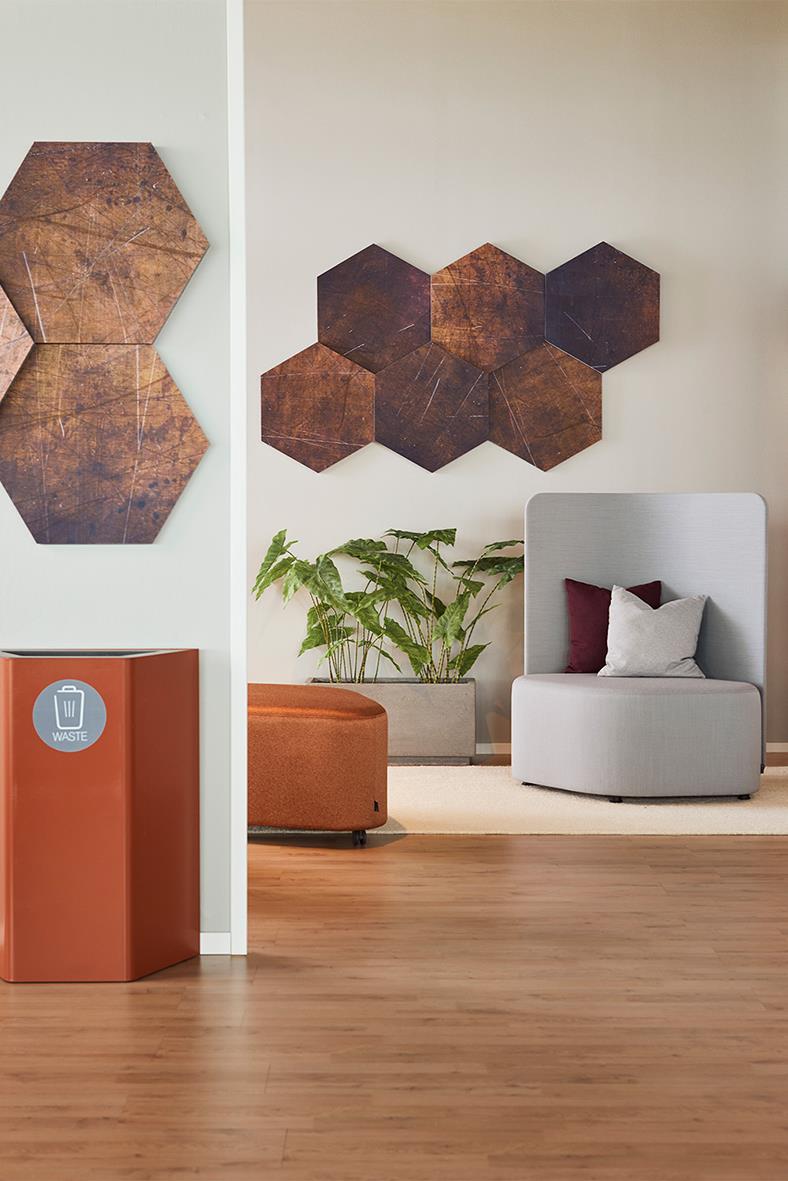 Ljudabsorberande Honey 6-pack i rostfärgat hexagonformat på vägg i modernt inrett rum med växt och sittmöbel