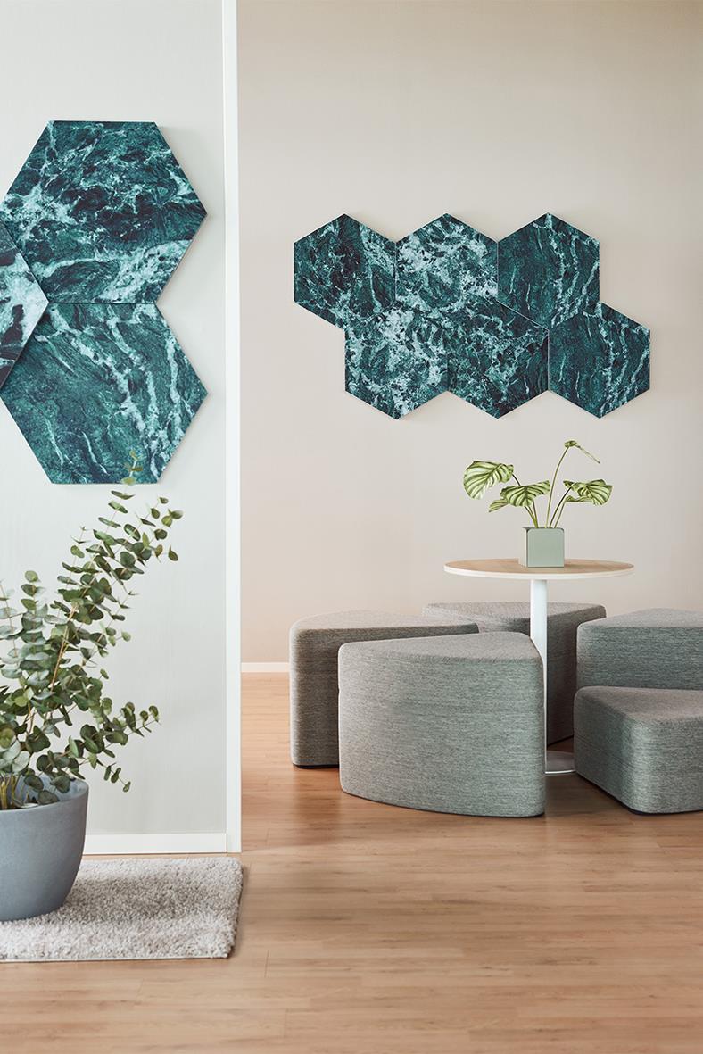 Ljudabsorberande hexagonala väggdekorationer i blå marmor på vägg i ett modernt vardagsrum med växter och sittgrupp