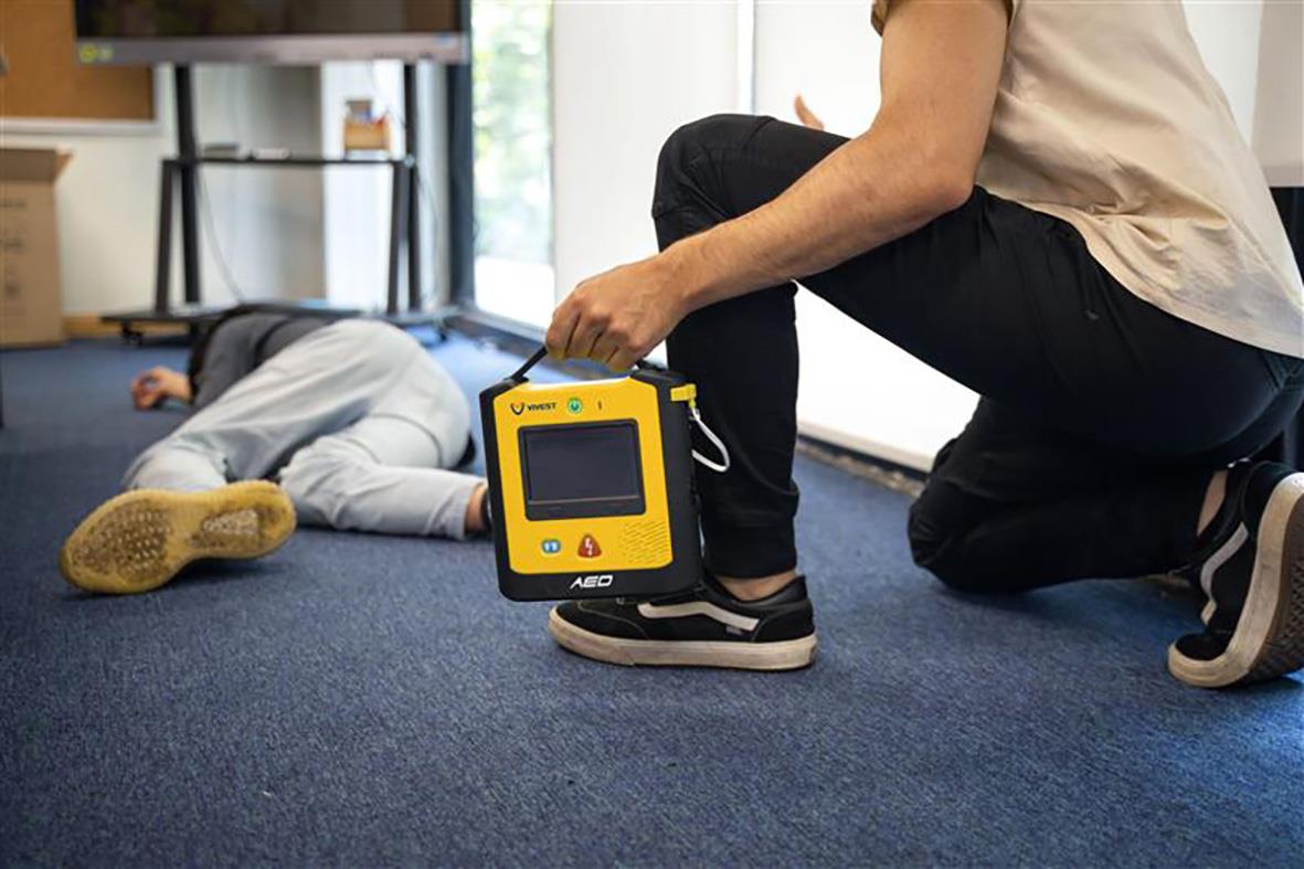 Person använder en hjärtstartare från ViVest Serie 3 på en person som ligger på golvet