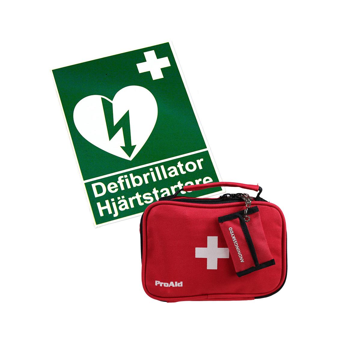Hjärtstartare och defibrillator i röd väska med vitt kors och informationsskylt