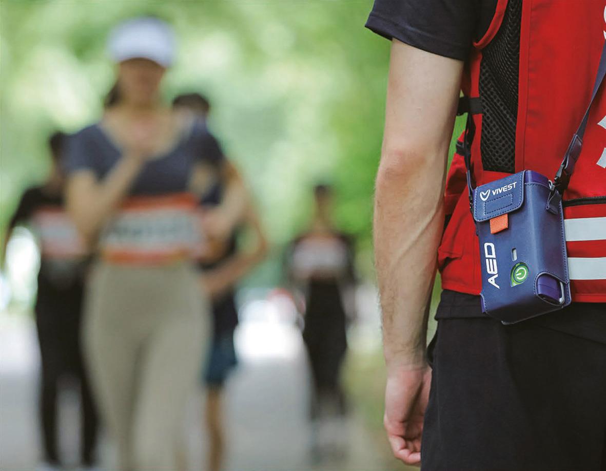 Person med Hjärtstartare ViVest Pocket 3 i fickan, andra personer i bakgrunden