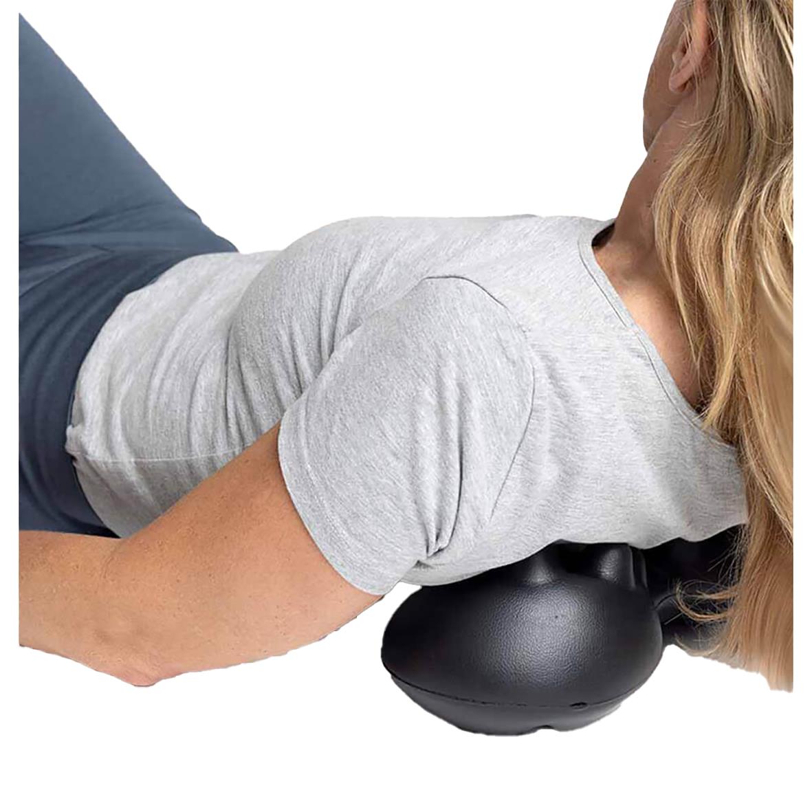 Kvinna använder massageboll för triggerpunktsbehandling i nacke och hållning
