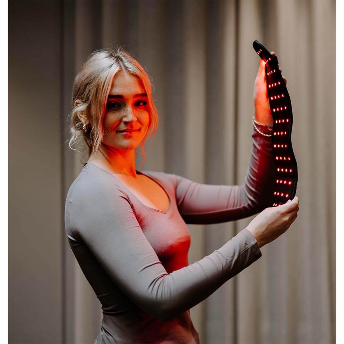 Kvinna håller ett bälte med infrarött ljus för posturstöd