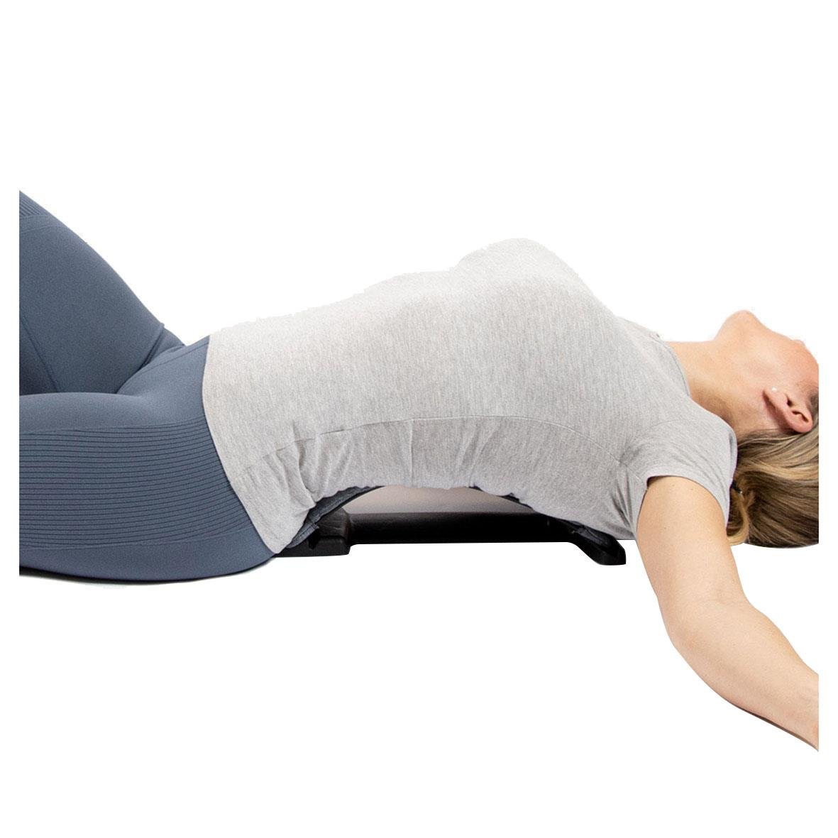 Kvinna ligger på mage på ryggsträckare för att förbättra hållningen