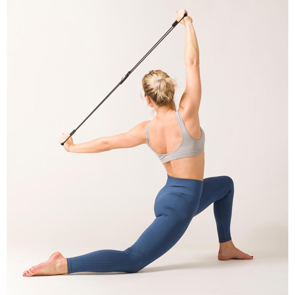 Kvinna använder träningsband för att förbättra hållning och styrka, i en stretchande position med ett träningsband över huvudet