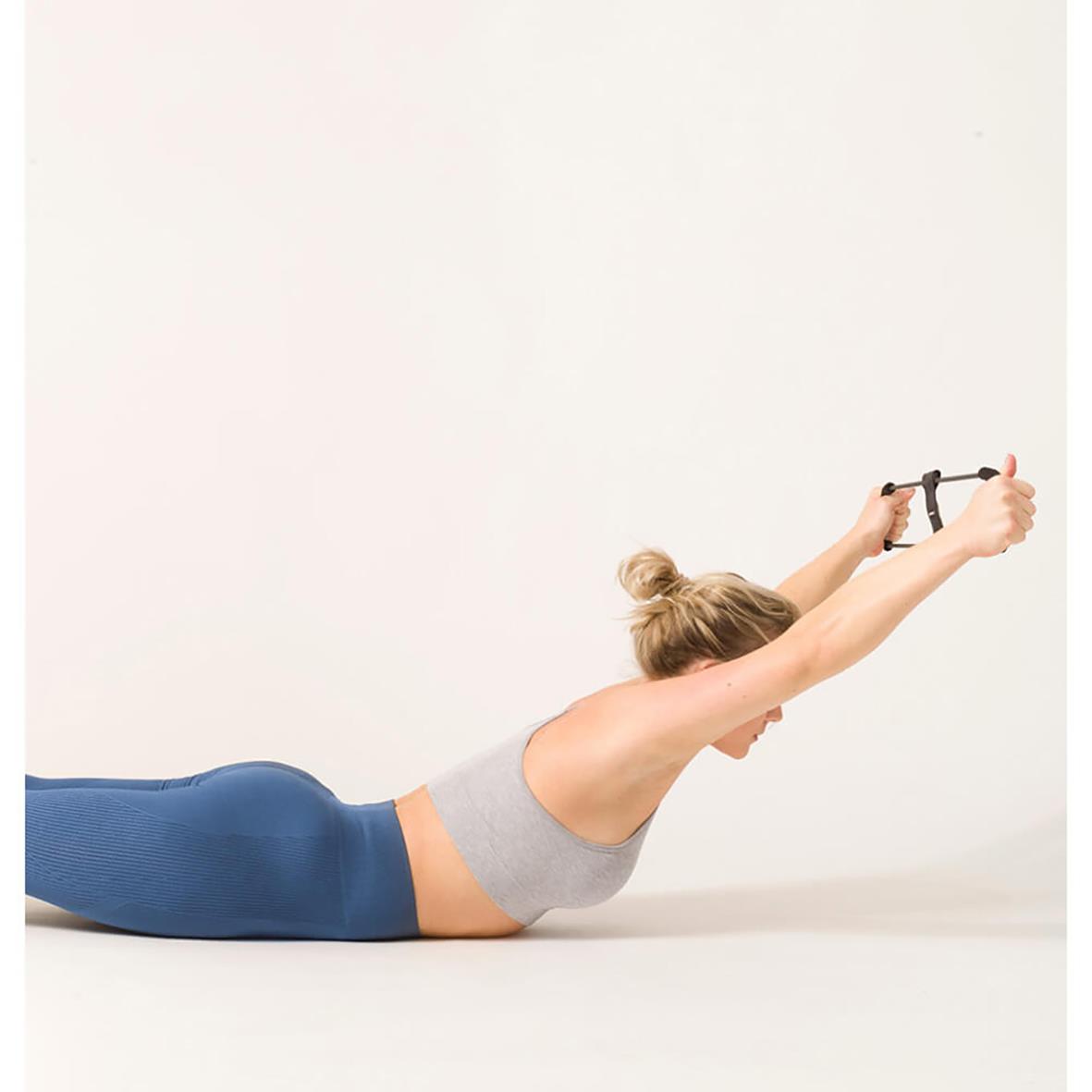 Kvinna gör övning med träningsband för hållning och styrka, liggande på mage med armar utsträckta framåt