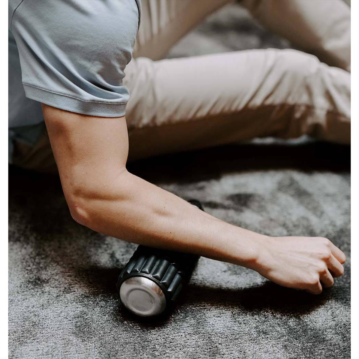 Person använder en Wavewell foam roller för muskelmassage på golvet