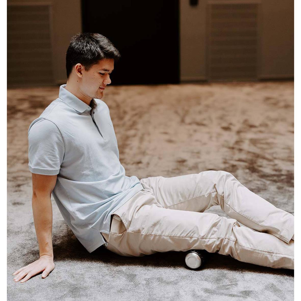 Person använder en Wavewell foam roller för att massera ryggen medan de sitter på en matta i ett rum