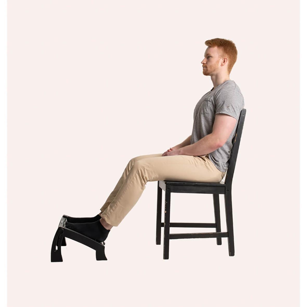 Man sitter på stol med fotstöd för ergonomisk sittposition