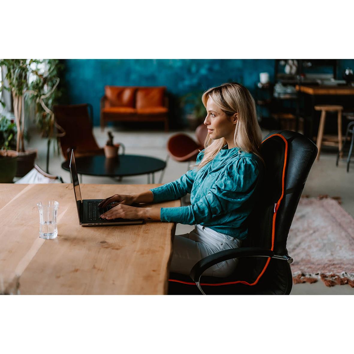 Kvinna sitter i en ergonomisk massagekudde med Medivon Cosy Mesh på kontoret