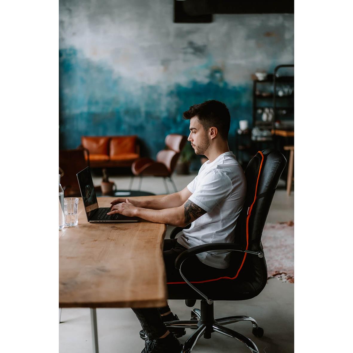 Man sitter vid ett skrivbord i ett kontor med en Medivon Cosy Mesh massagesits