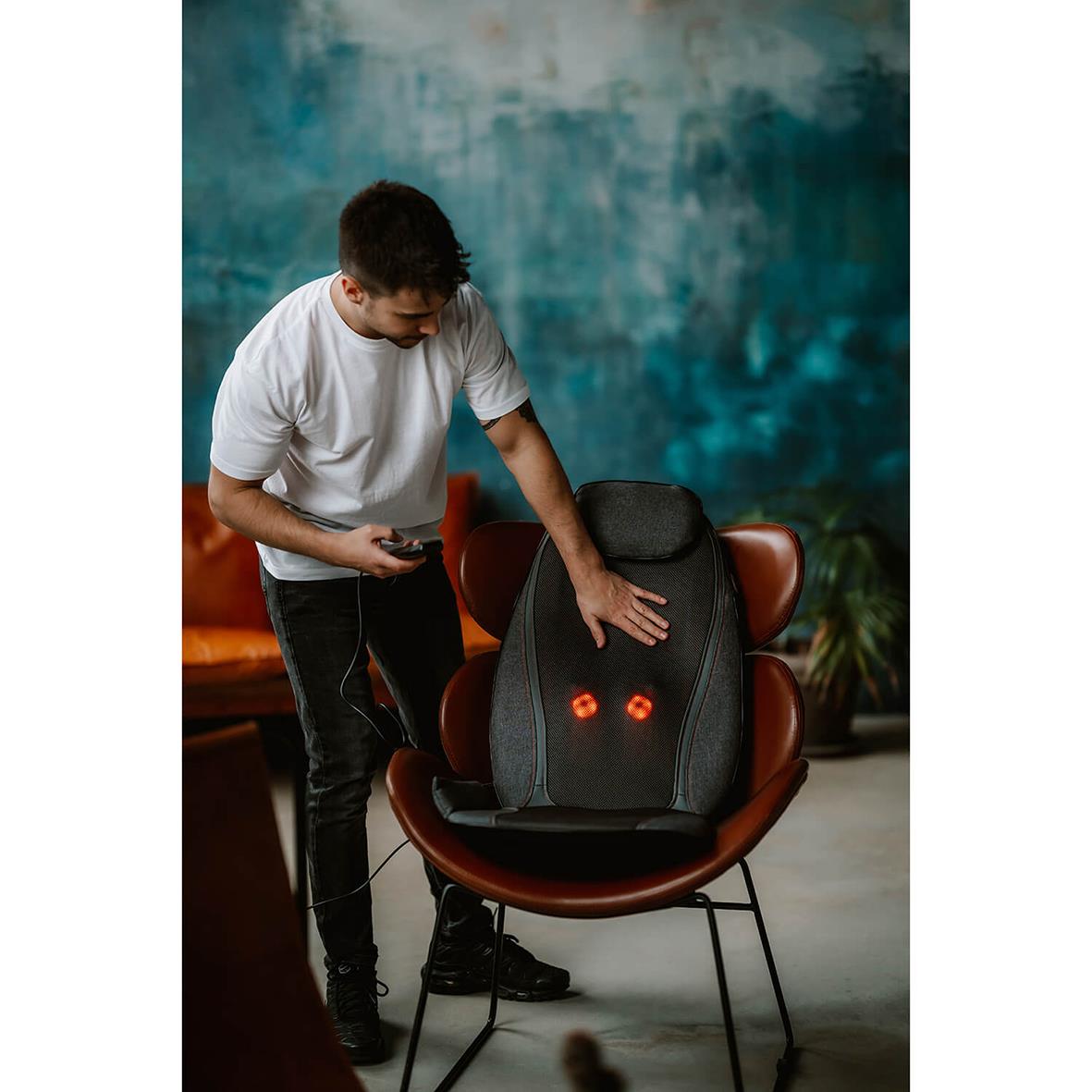 Man provar massagefåtölj Medivon Cosy Shiatsu i ett rum med blå vägg och växter