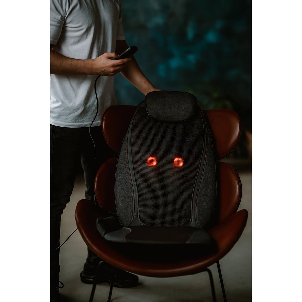 Massagesits Medivon Cosy Shiatsu på en modern stol med kontrollenhet i handen