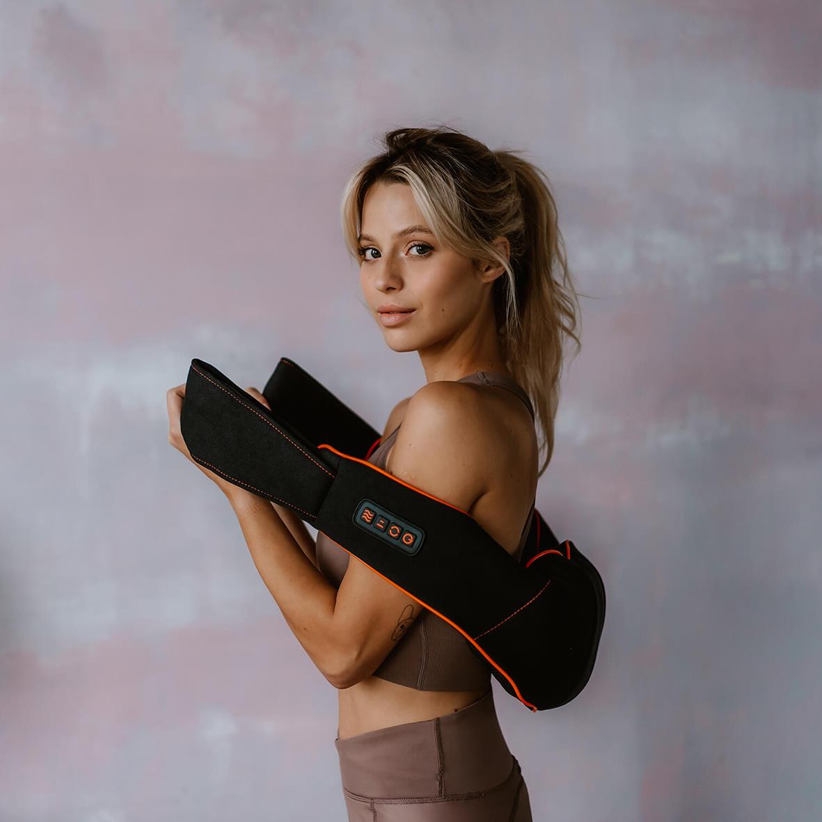 Kvinna använder nackmassageapparat Medivon Simple svart, bär den på axeln