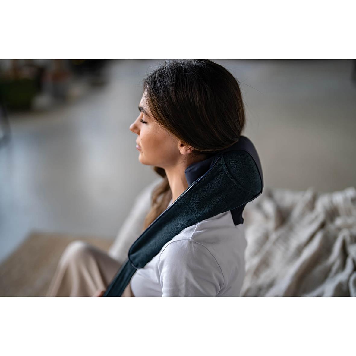 Kvinna använder nackmassageapparat Medivon Hyperion, sitter avslappnad hemma