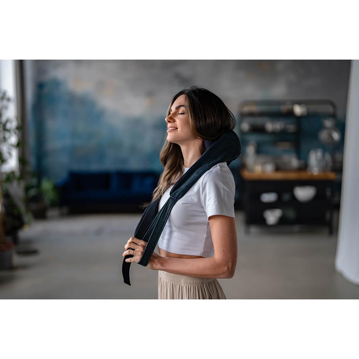 Kvinna använder nackmassageapparat Medivon Hyperion i ett rum med industriell stil