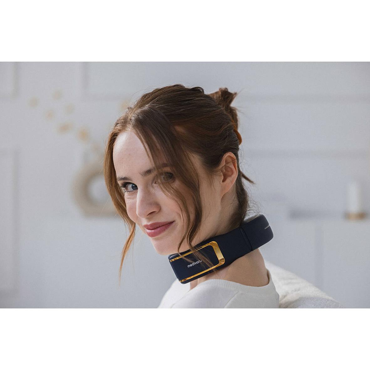 Kvinna använder nackmassageapparat Medivon Ultra EMS Pro runt halsen i ett hem