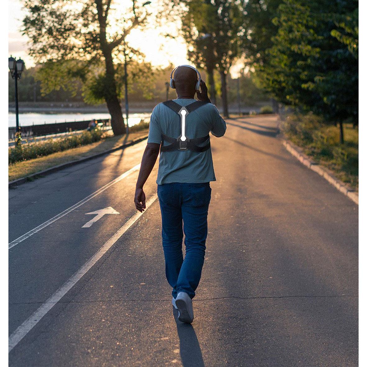 Person som går på vägen med reflexband och hållningsband på ryggen, solnedgång i bakgrunden