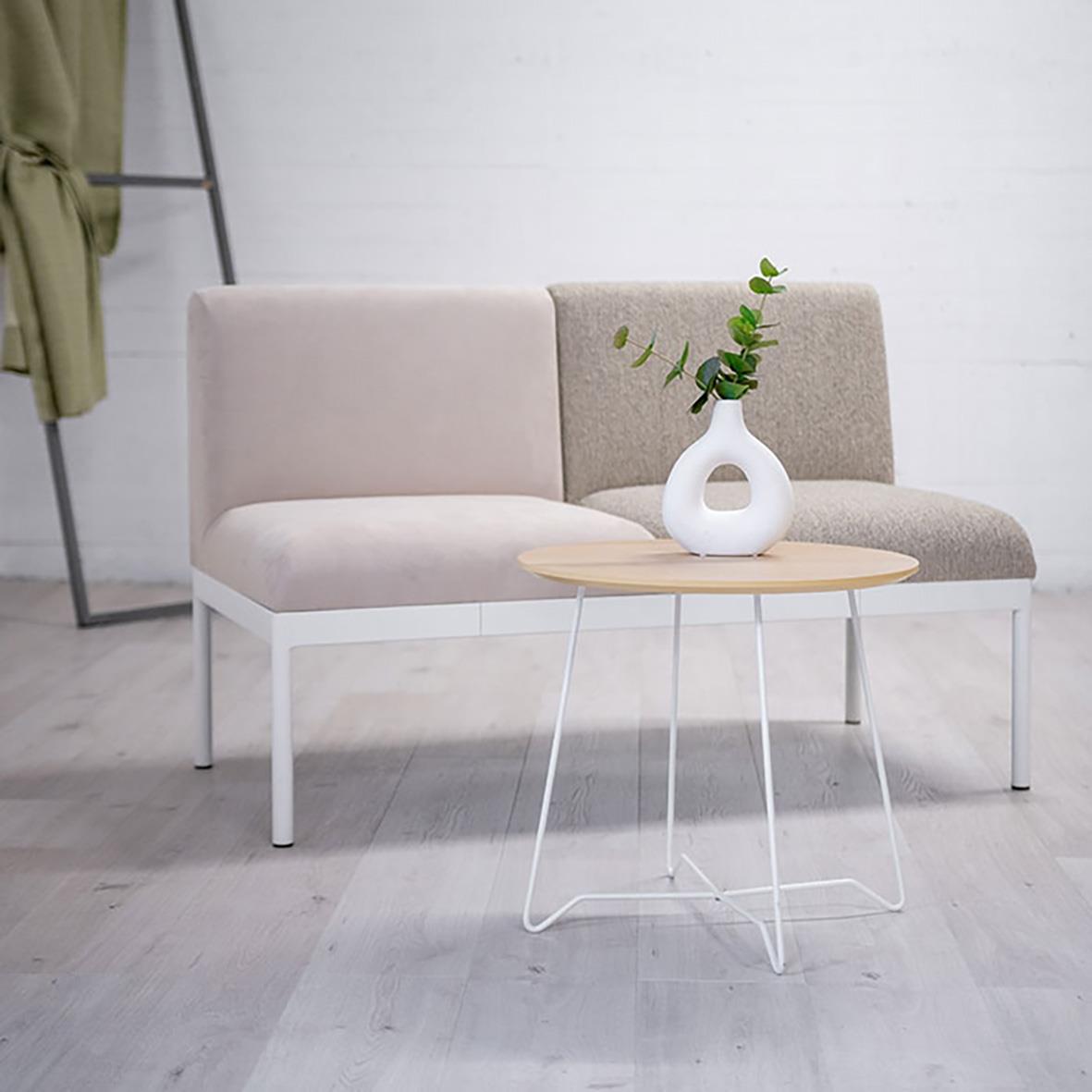 Vitt och beige soffbord med växt i vit vas framför en tvåfärgad soffa i ett minimalistiskt vardagsrum