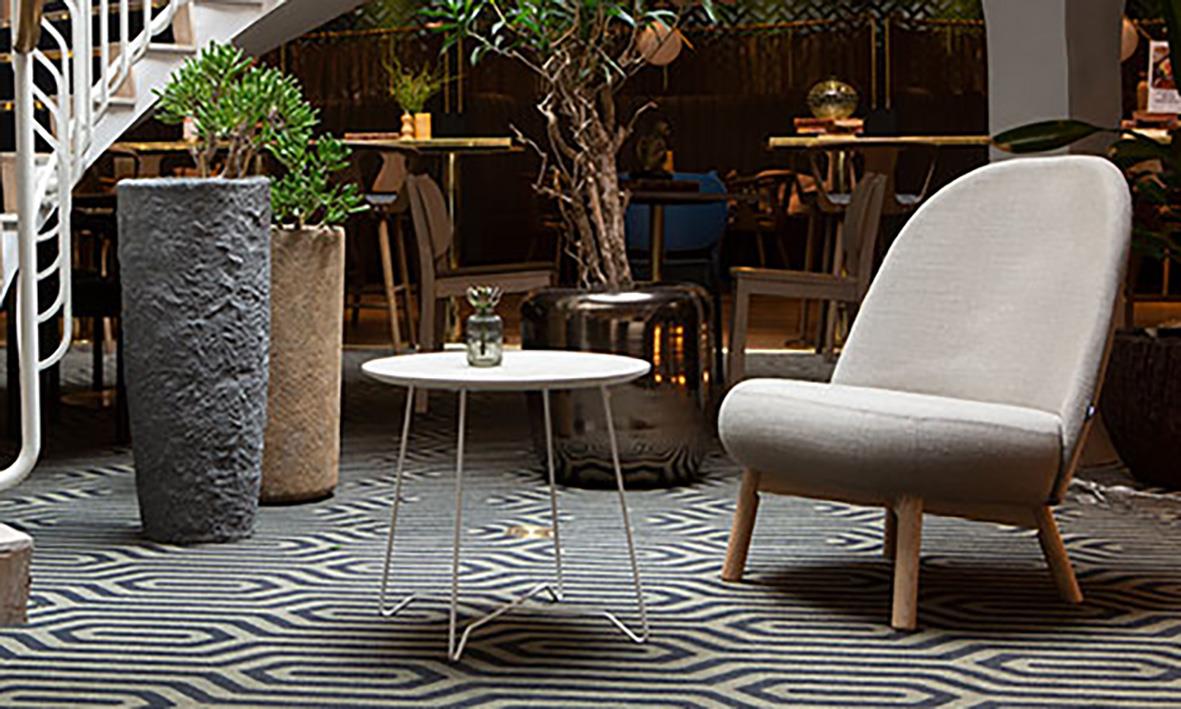 Bekvämt sittmöbel och liten rund bord i ett modernt inomhusmiljö med växter och trädet i bakgrunden