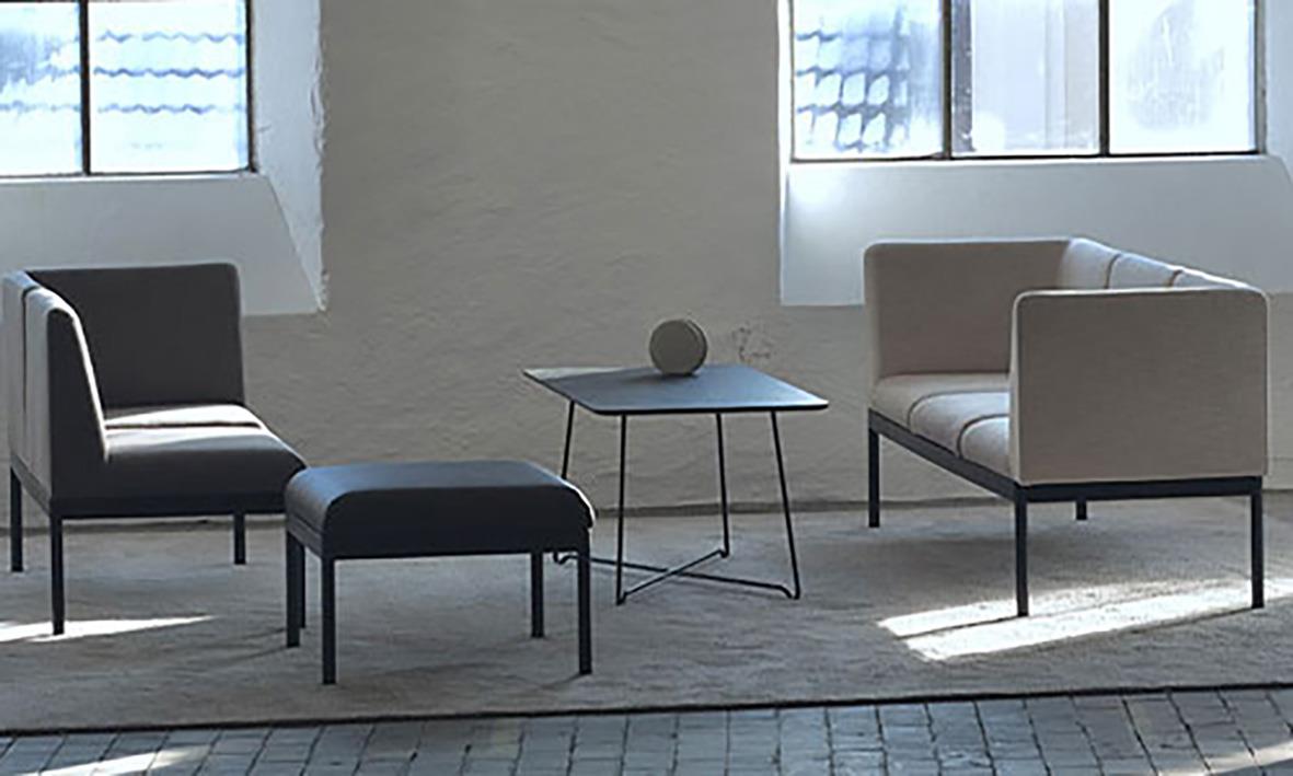 Vardagsrum med tre stolar, ett bord och stora fönster som släpper in ljus