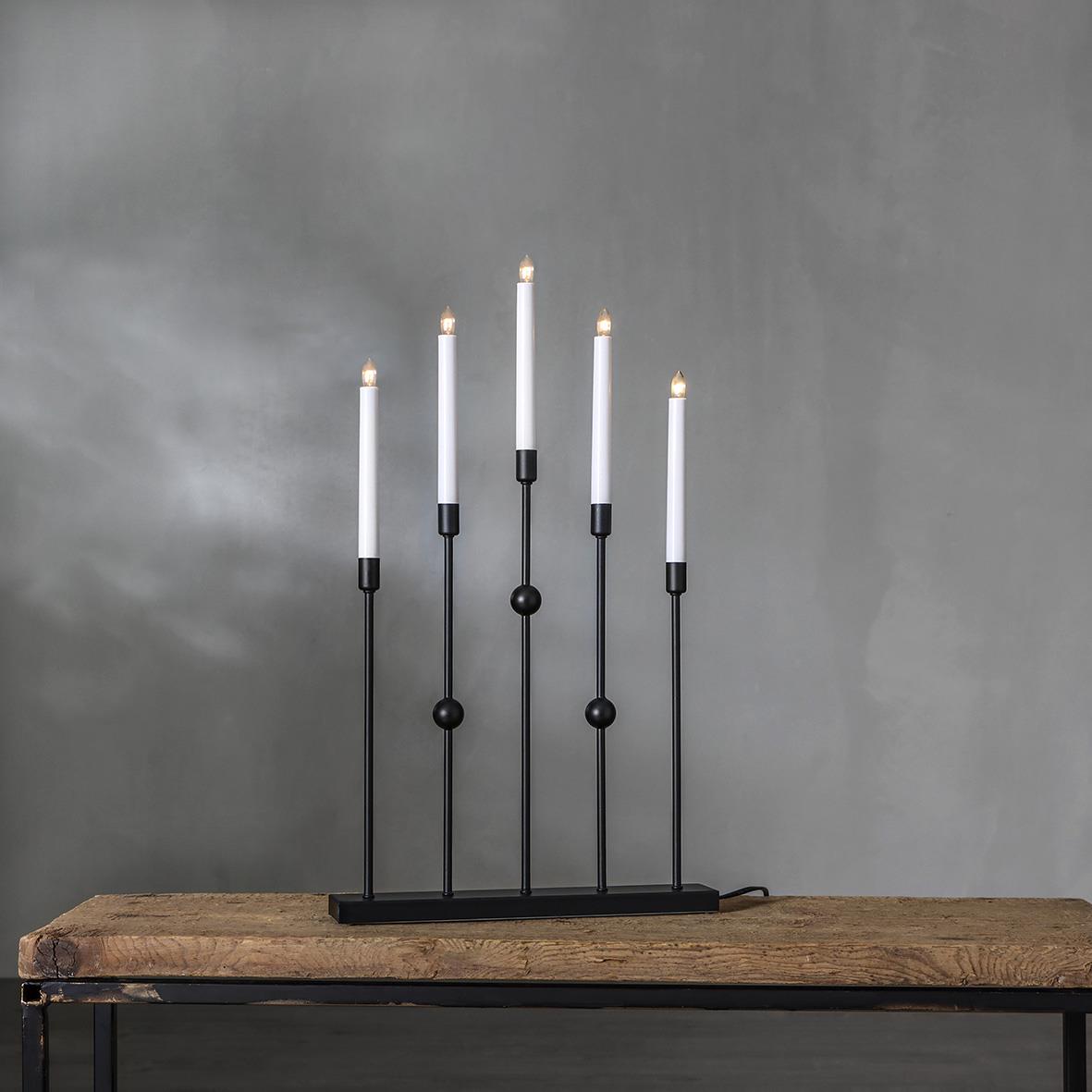 Ljusstake med fem ljus i svart metall på en träbord