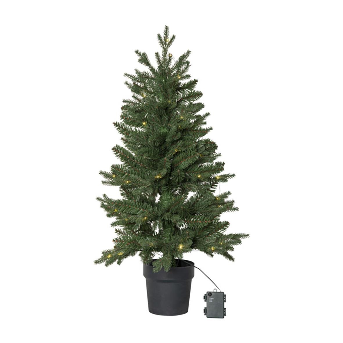 En konstgjord julgran i svart kruka med en kontrollenhet bredvid