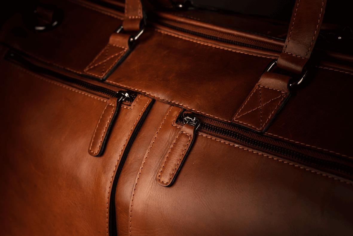 Närbild av en cognacfärgad skinn weekendbag med dragkedjor och handtag