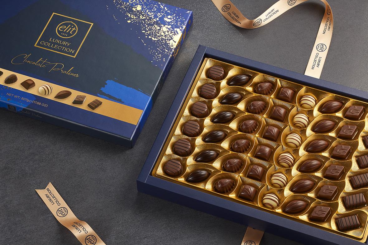 Ljusblå chokladask med gulddetaljer och ett urval av praliner i olika former och mönster