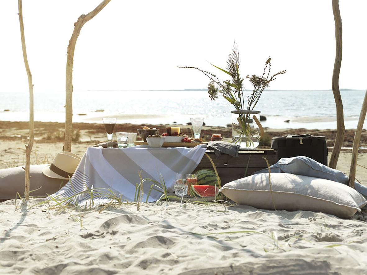 Kylväska Sagaform City Stor Svart 22x34x28cm 20L på strand med bord, stolar och hav i bakgrunden