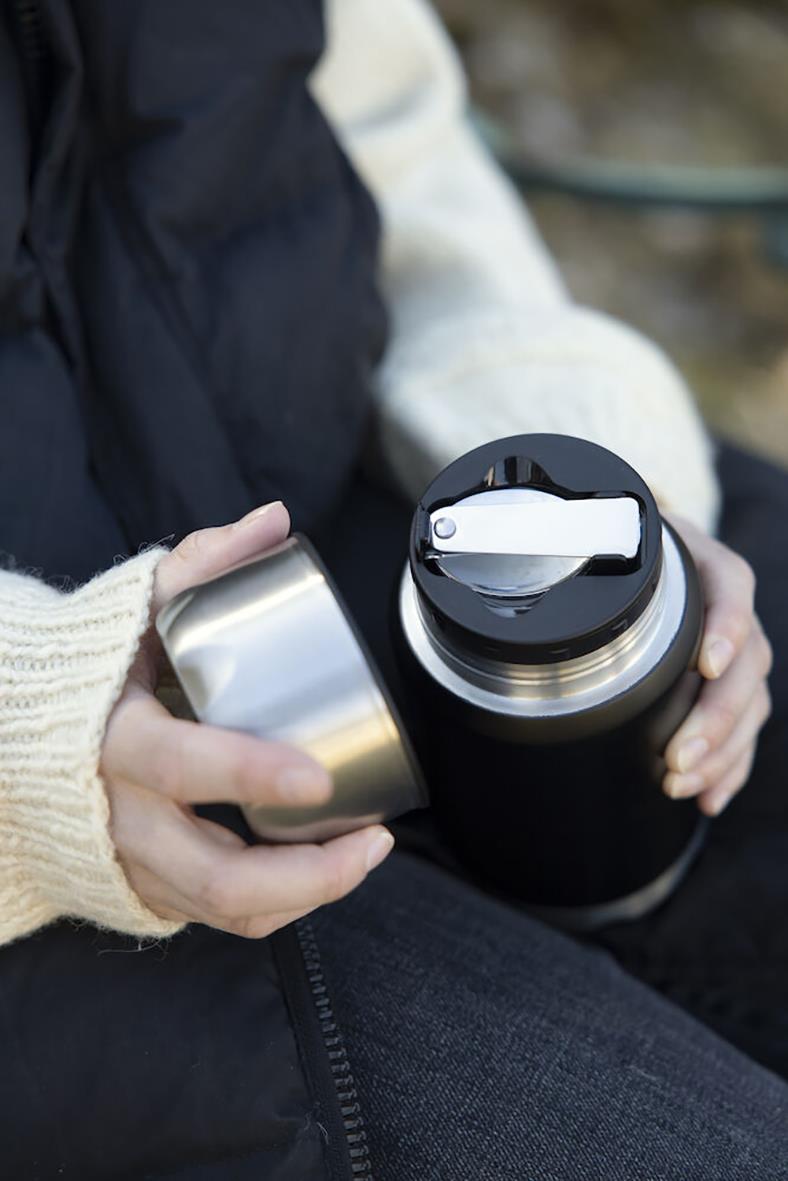 Person öppnar en svart termosmugg från Sagaform med svart lock, använd för dryck på språng