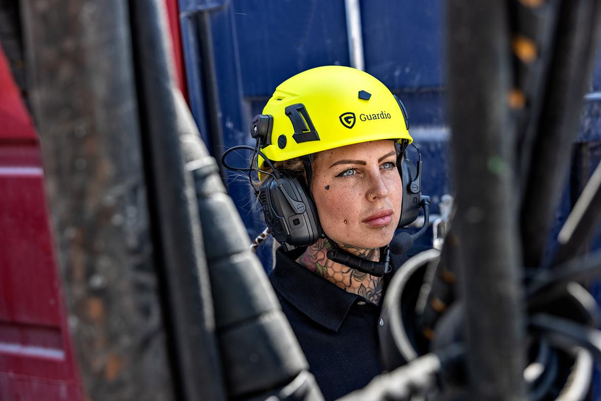 Person i skyddshjälm och hörselskydd bland metallrör