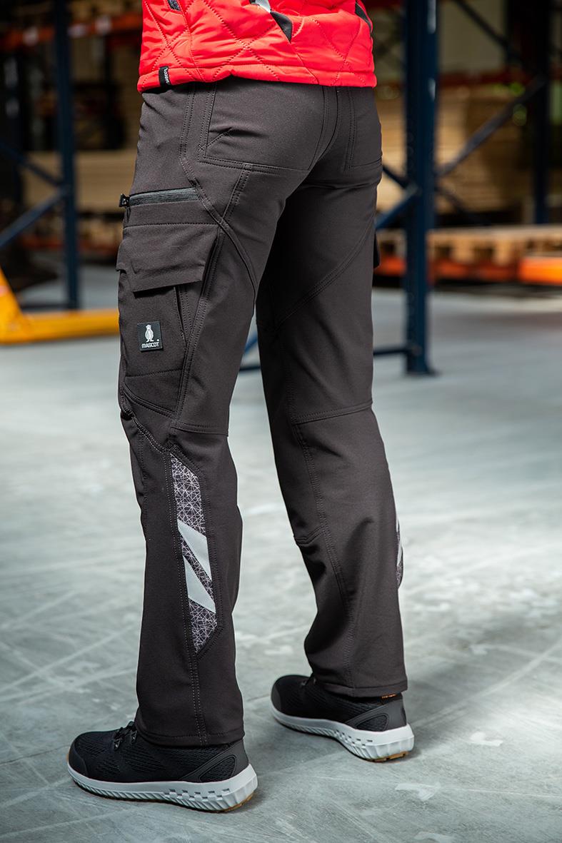 Svarta arbetsbyxor med flera fickor och reflexdetaljer, bärs av person i lagerlokal