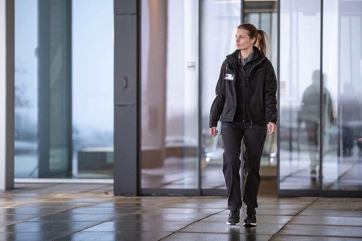 Kvinna i svart funktionsbyxa och jacka går i en modern byggnad