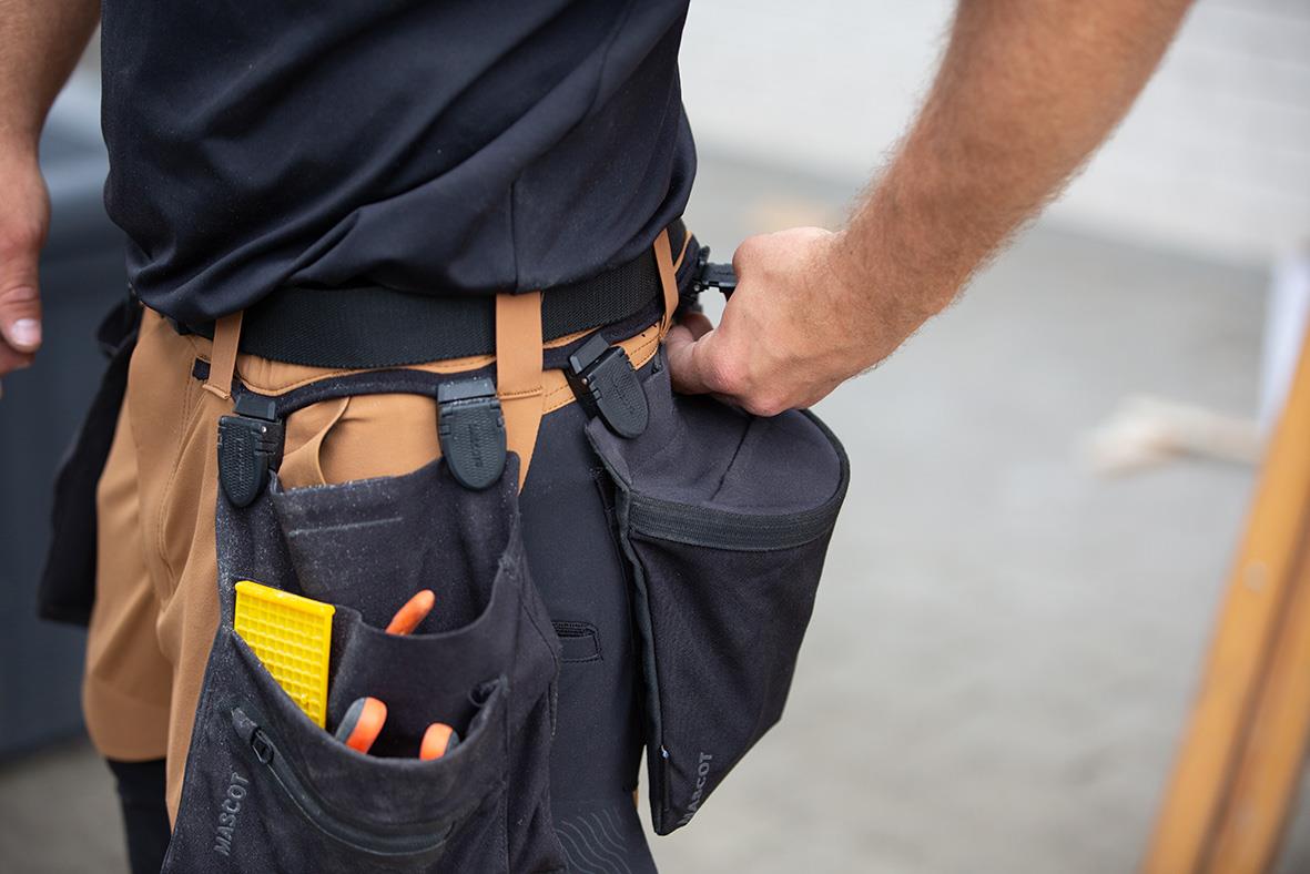 Person med verktygsbälte med fickor och verktyg, klädd i shorts